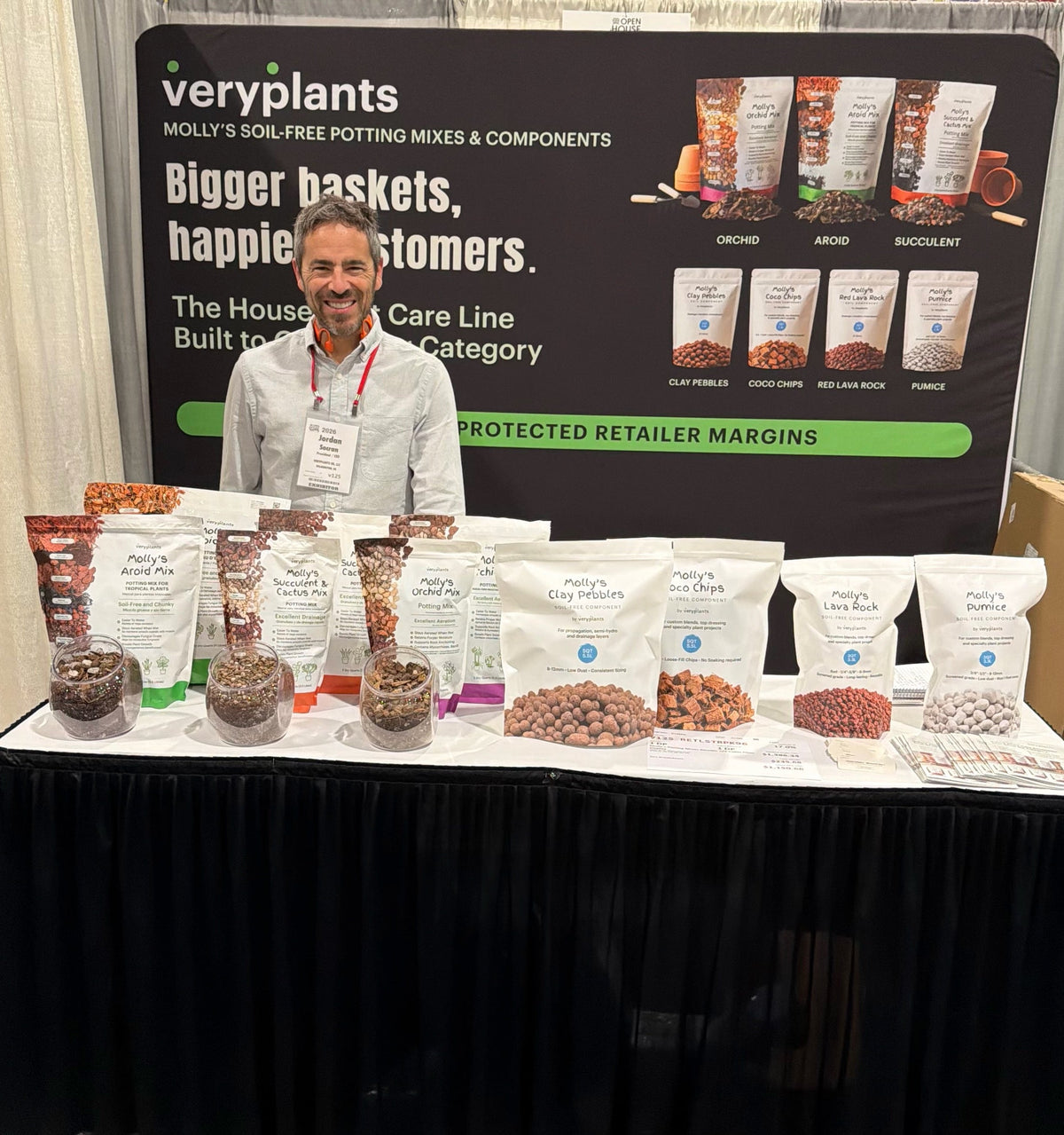 Jordan Socran at the Veryplants display at Arett Sales Open House, with Molly's potting mixes, Clay Pebbles, Coco Chips, Red Lava Rock, and Pumice on the table.